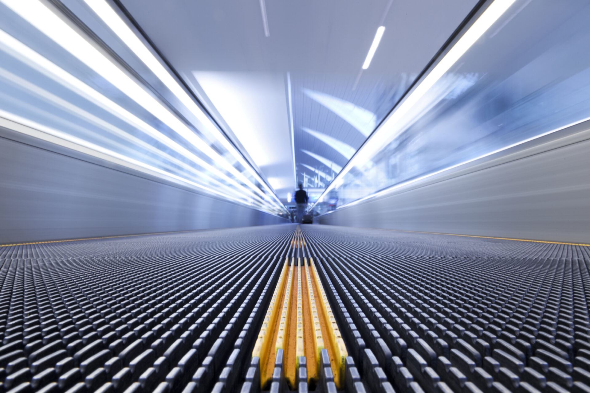 Person on a moving escalator with yellow stripes