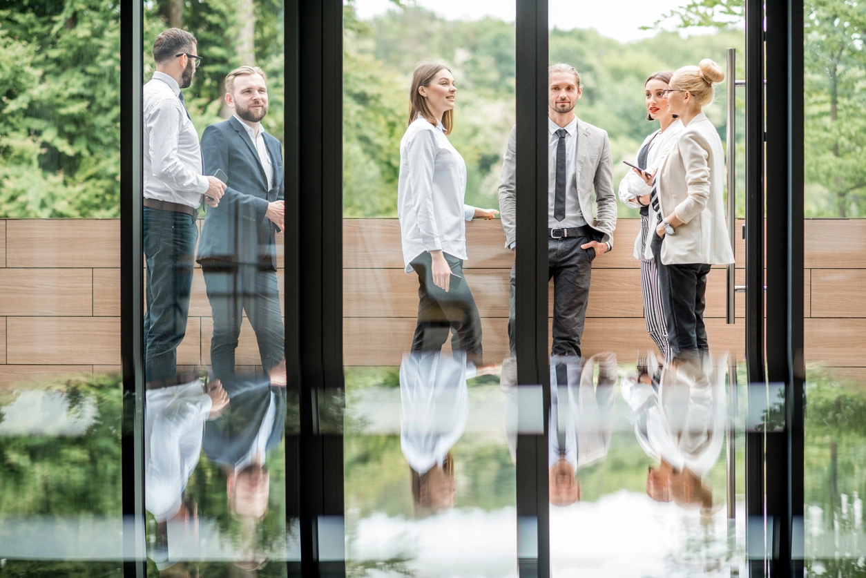 Business professionals in conversation in a glass-walled office